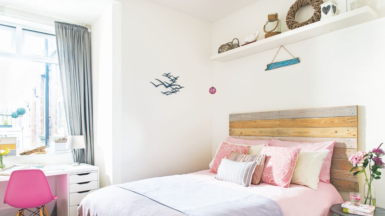 coastal bedroom ideas with white walls, driftwood style headboard, shelf with nautical accessories, desk, side table pink and grey bedding 