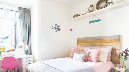 coastal bedroom ideas with grey bed, blue pattered bedding, nautical cushions, weathered stool, shelf with nautical accessories, vintage painting 