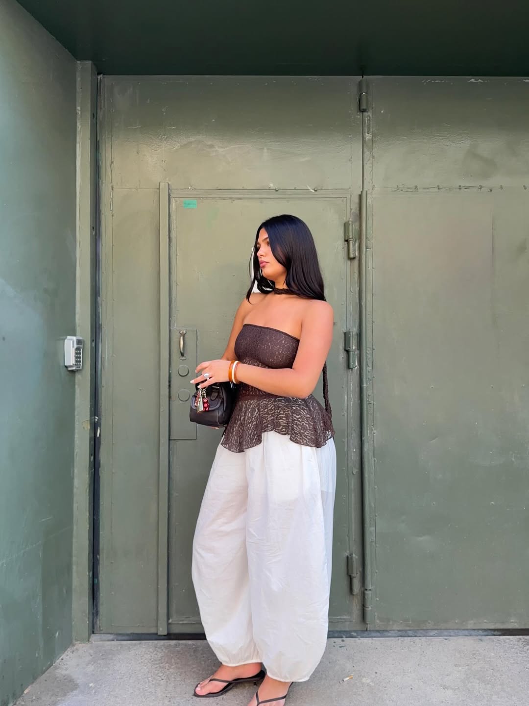 @isabellecoheen wears heeled flip-flops with a brown lace bandeau and white barrel trousers