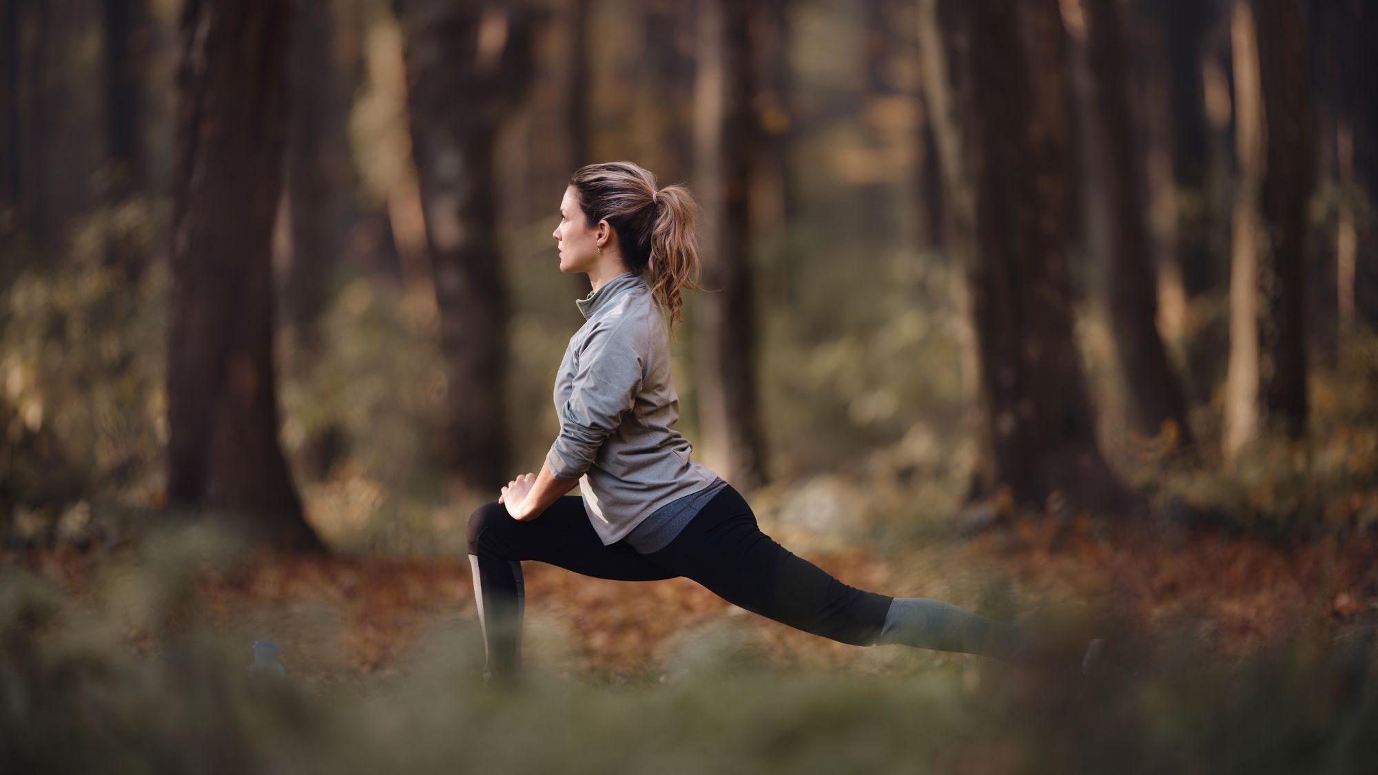 Working out in winter: A woman stretching in an autumnal-looking forest