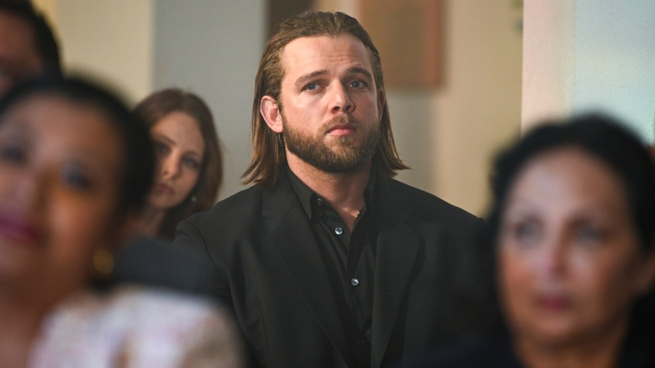 Max Thieriot como Bode luciendo sombrío mientras está sentado en el banco de una iglesia en el final de la temporada 2 de Fire Country.