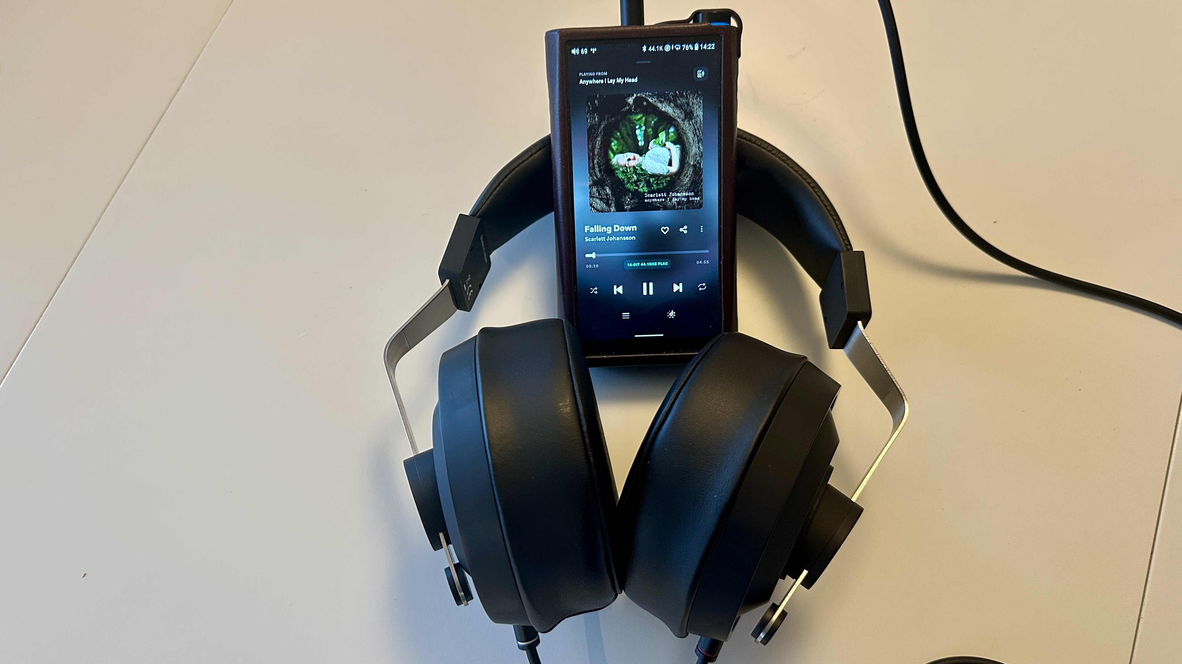 Close ups of the Final DX3000CL with a hi-res digital audio player, showing the ear cups, arm and screen on the player, all on beige background