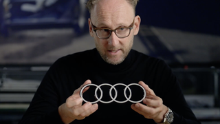 A man holding a model of the Audi logo