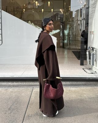 Stylish and fashion influencer Monikh Dale on the street in Europe wearing a chic fall outfit styled with a woven leather bag.