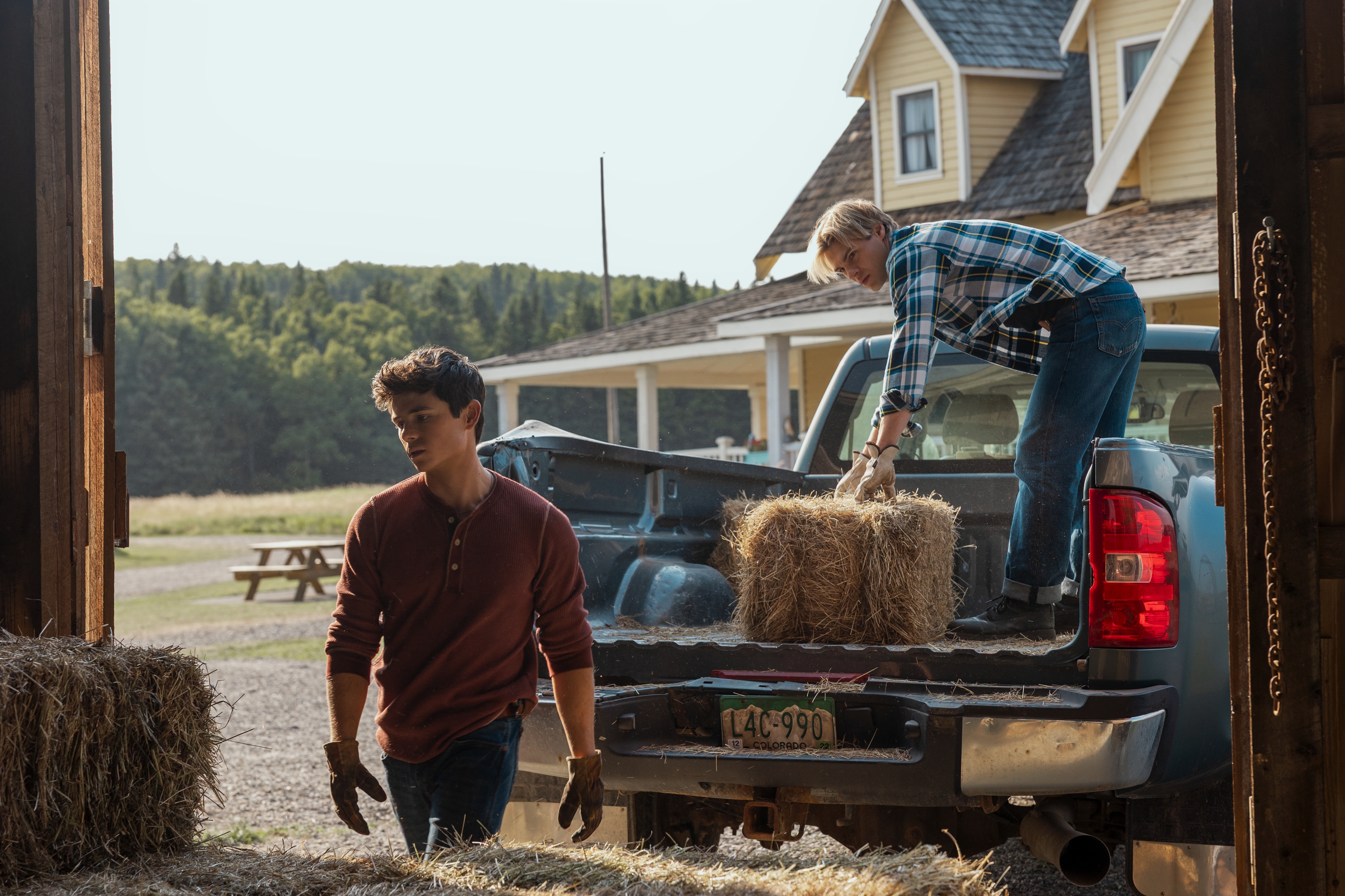 Ashby Gentry as Alex and Noah LaLonde as Cole working in the barn picking up hay in My Life with the Walter Boys season 2