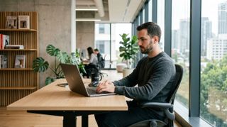 a man building a website on a macbook in a minimalist office