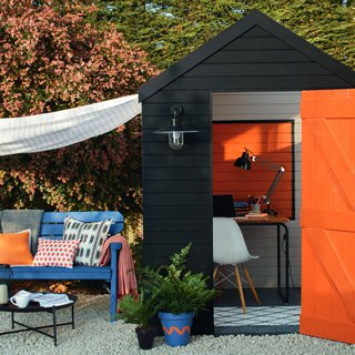 orange and black garden shed blue bench with pillows plant and trees