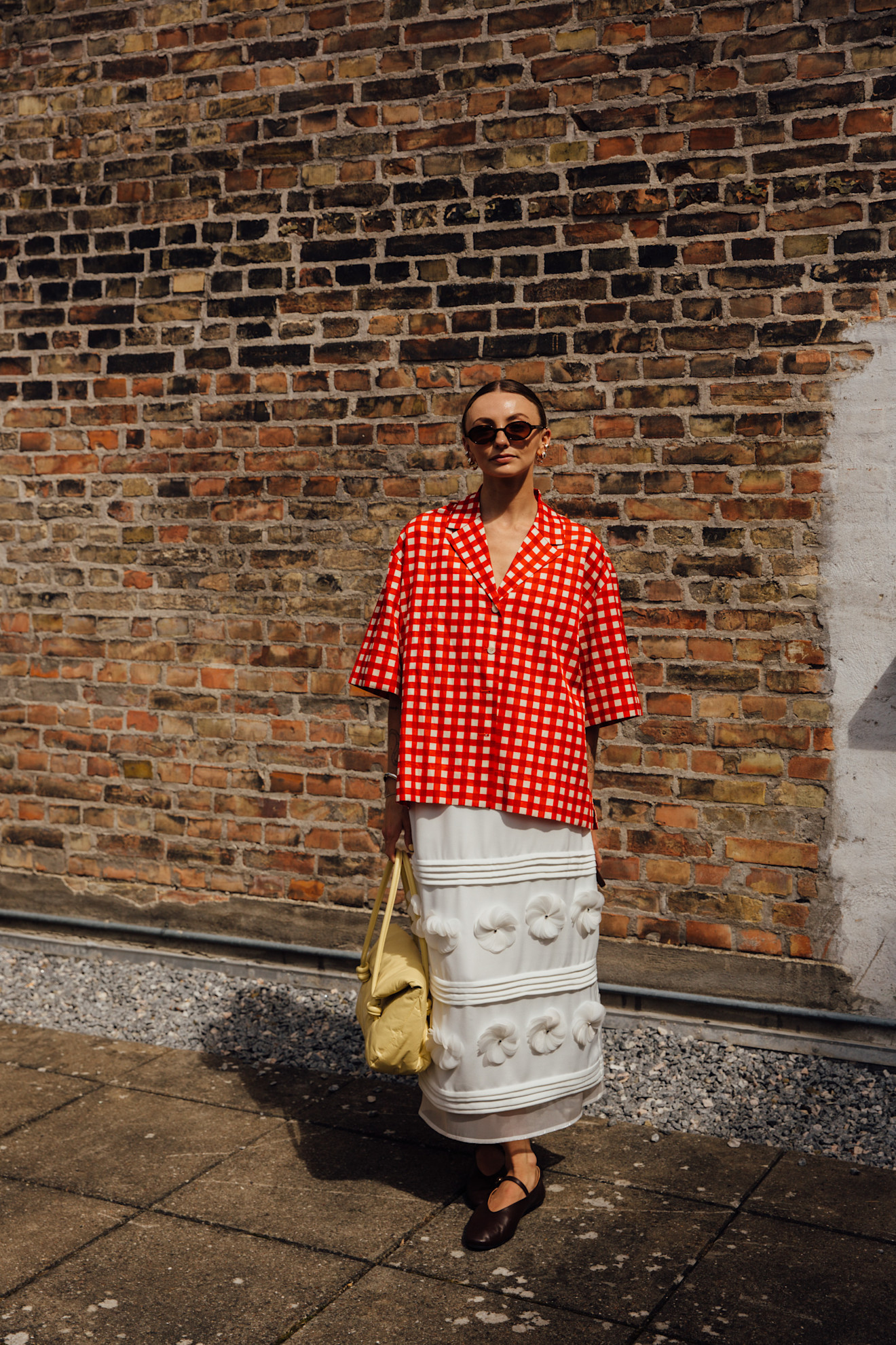 woman wearing red top, white skirt, yellow bag, and black shoes