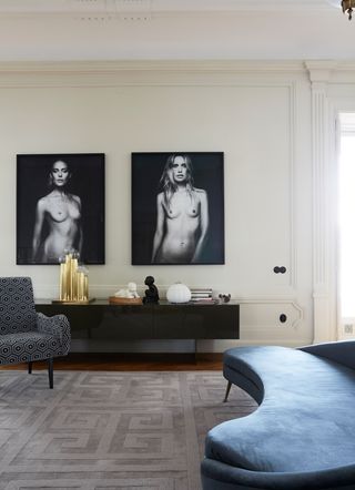 White living room with blue velvet sofa and monochrome prints