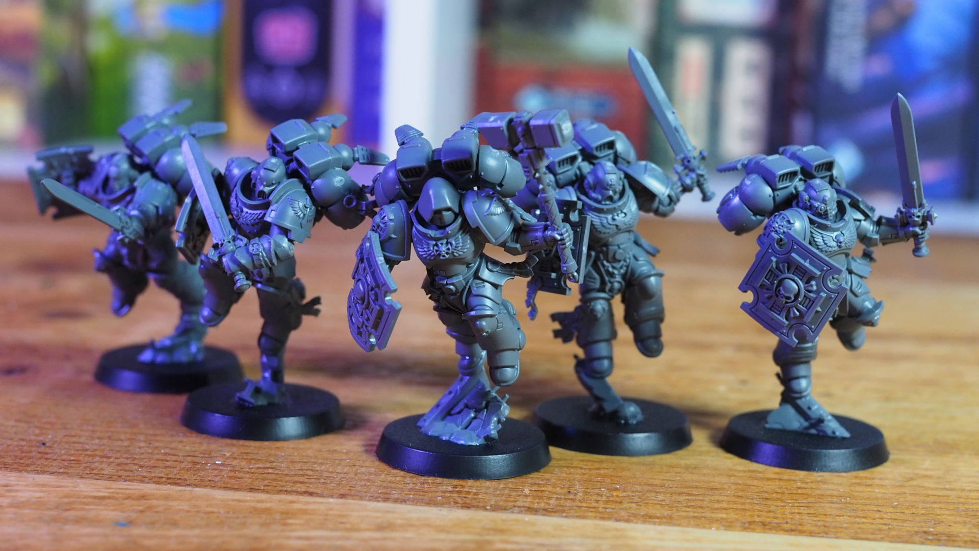 Vanguard Veterans with Jump Packs on a wooden surface, against blurred board games