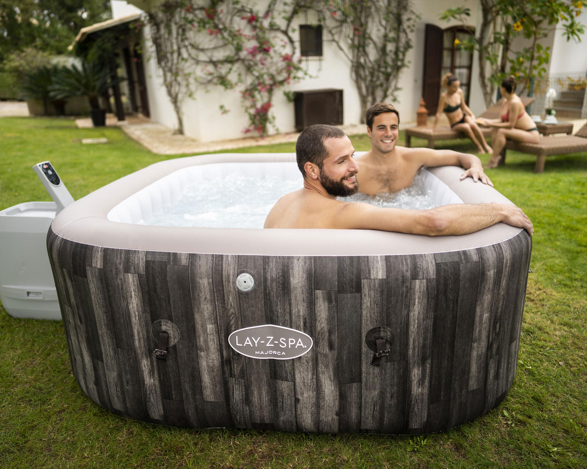 tow men sitting in a hot tub in a garden