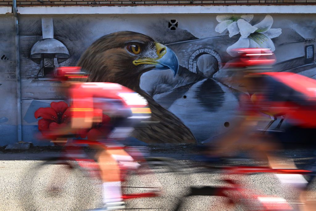 ALTURA SPAIN FEBRUARY 04 Riders pass in front of a graffitiduring the 74th Volta a la Comunitat Valenciana 2023 Stage 4 a 1816km stage from Burriana to Alto de la Cueva Santa Altura 832m VCV2023 VoltaValenciana on February 04 2023 in Altura Spain Photo by Dario BelingheriGetty Images
