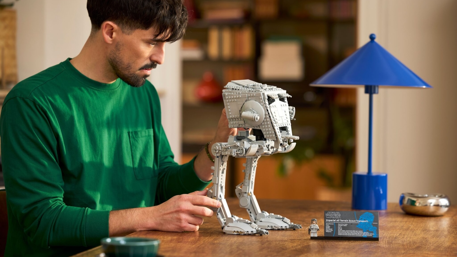 A man pointing his AT ST LEGO set towards a lamp 