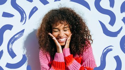 A smiling woman with frizzy hair and curls on a blue backdrop