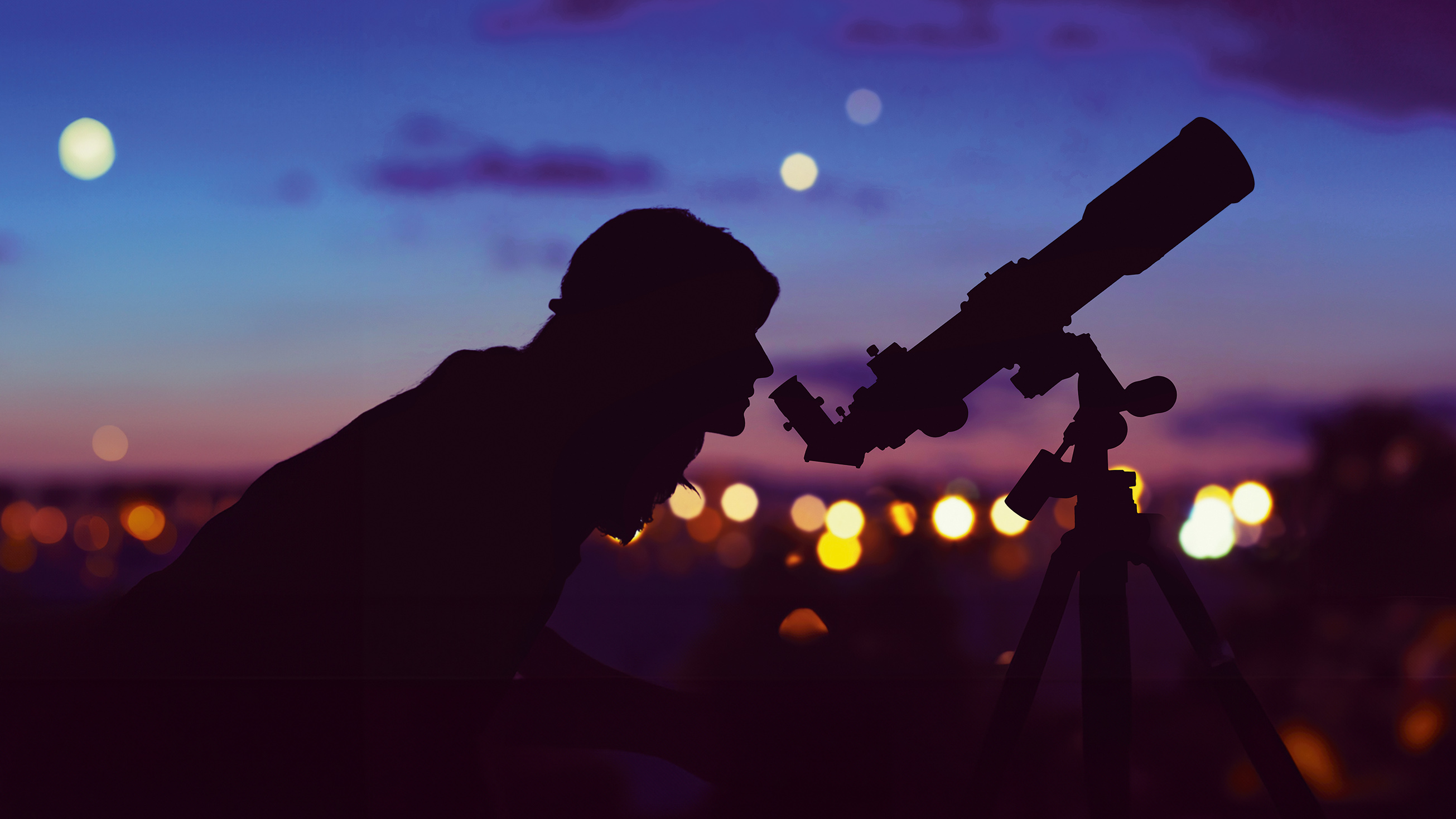 Girl looking at the stars with telescope beside her and de-focused city lights. My astronomy work.