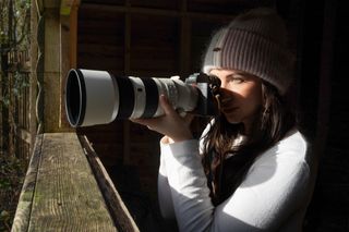 A woman in a hide using a camera and telephoto lens