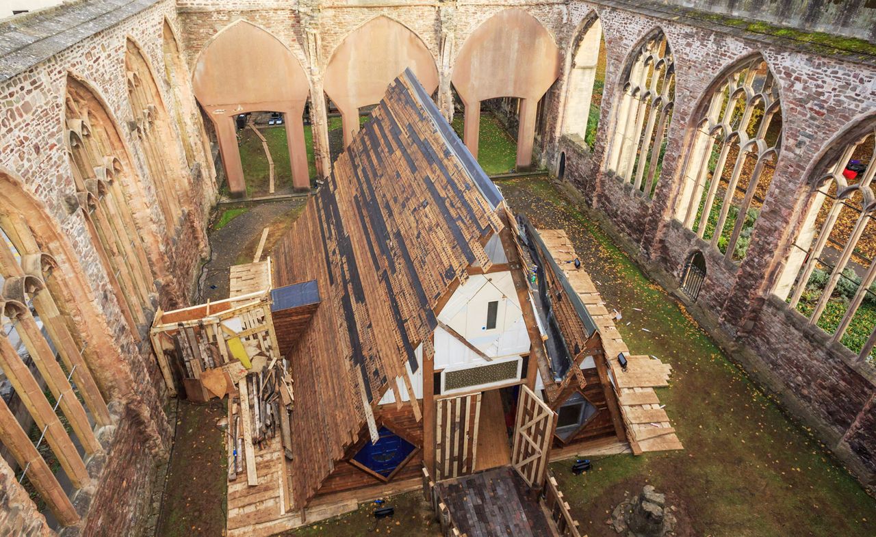 Construction-style image of a triangular-shaped house inside the arched walls of a church