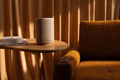Bose lifestyle collection speaker on a side table next to a yellow sofa