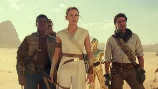 three people stand in a desert looking concerned there is a Wookie and a golden robot in the shape of a human behind them.