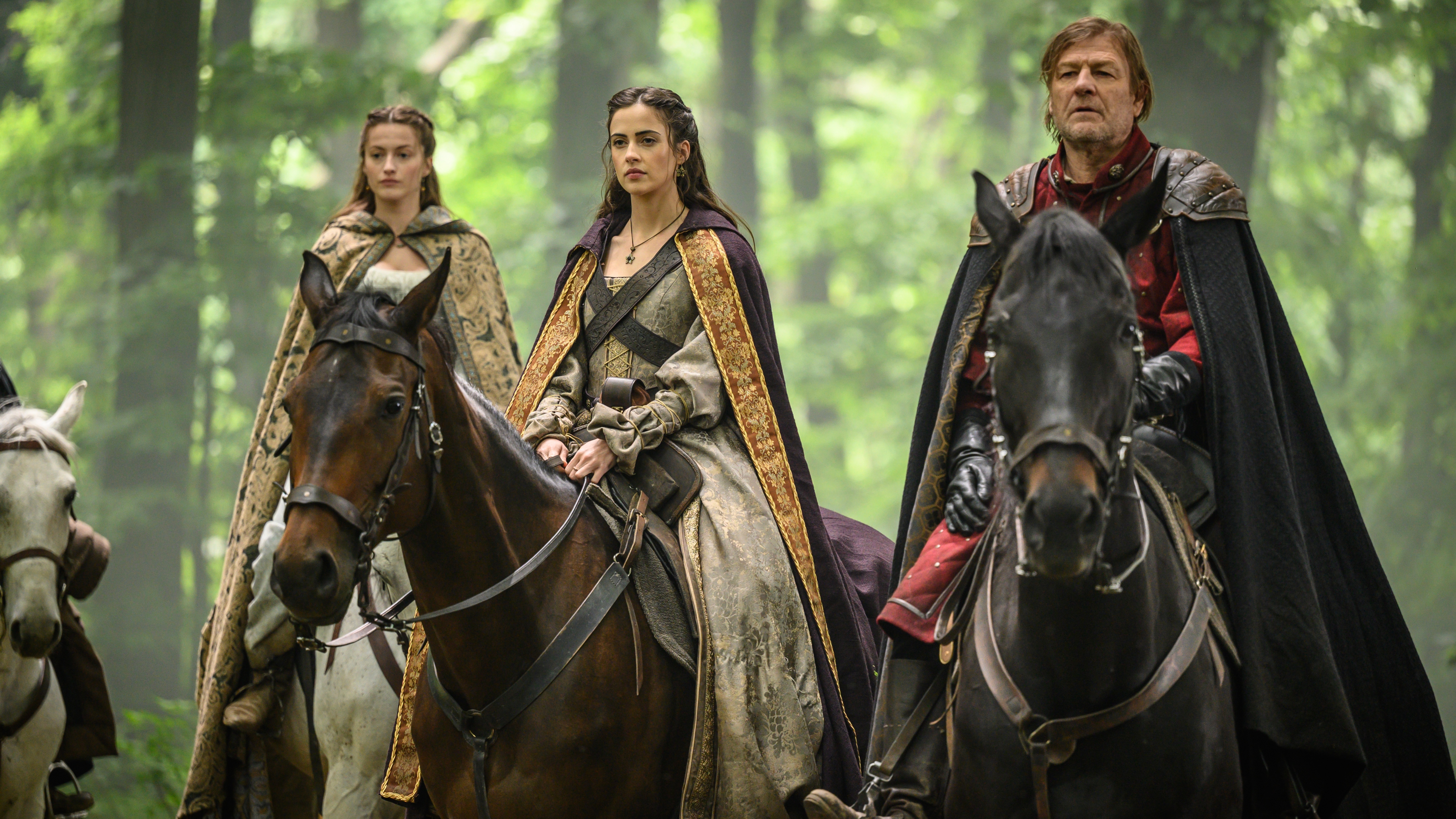 Maid Marian (Lauren McQueen), Priscilla of Nottingham (Lydia Peckham) and the Sheriff of Nottingham (Sean Bean) sitting on horses in the forest in Robin Hood.