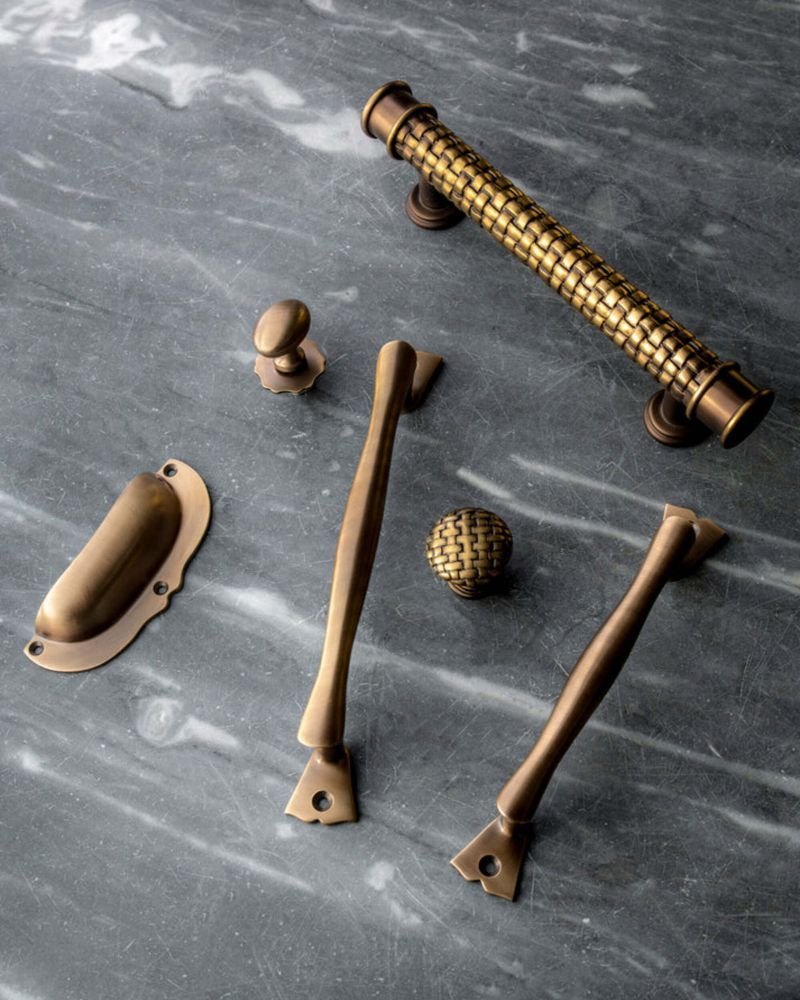 bronze, basketweave shaped hardware arranged on a black marble countertop