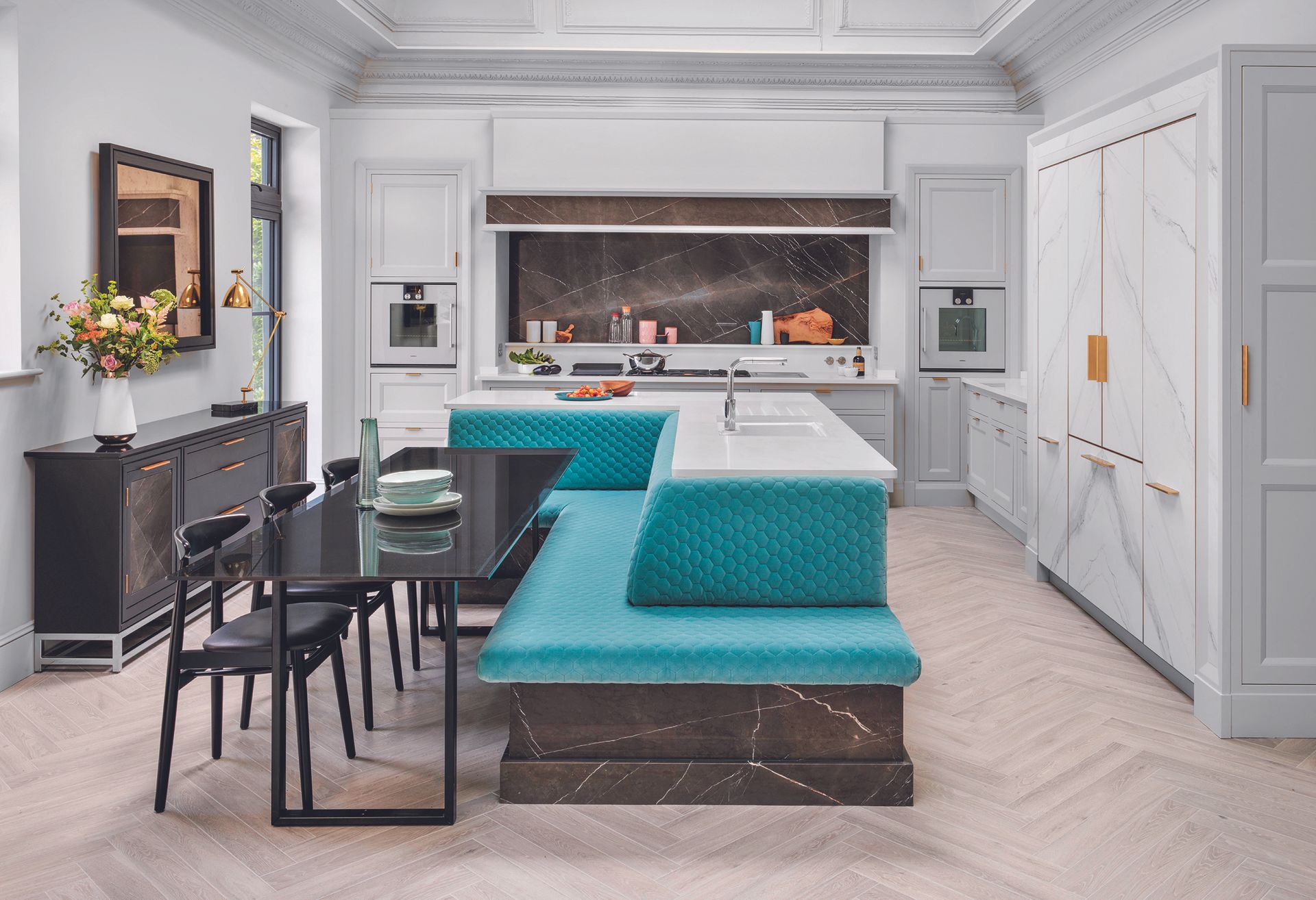 Kitchen island ideas featuring turquoise banquette seating and a black dining table in a large white scheme.