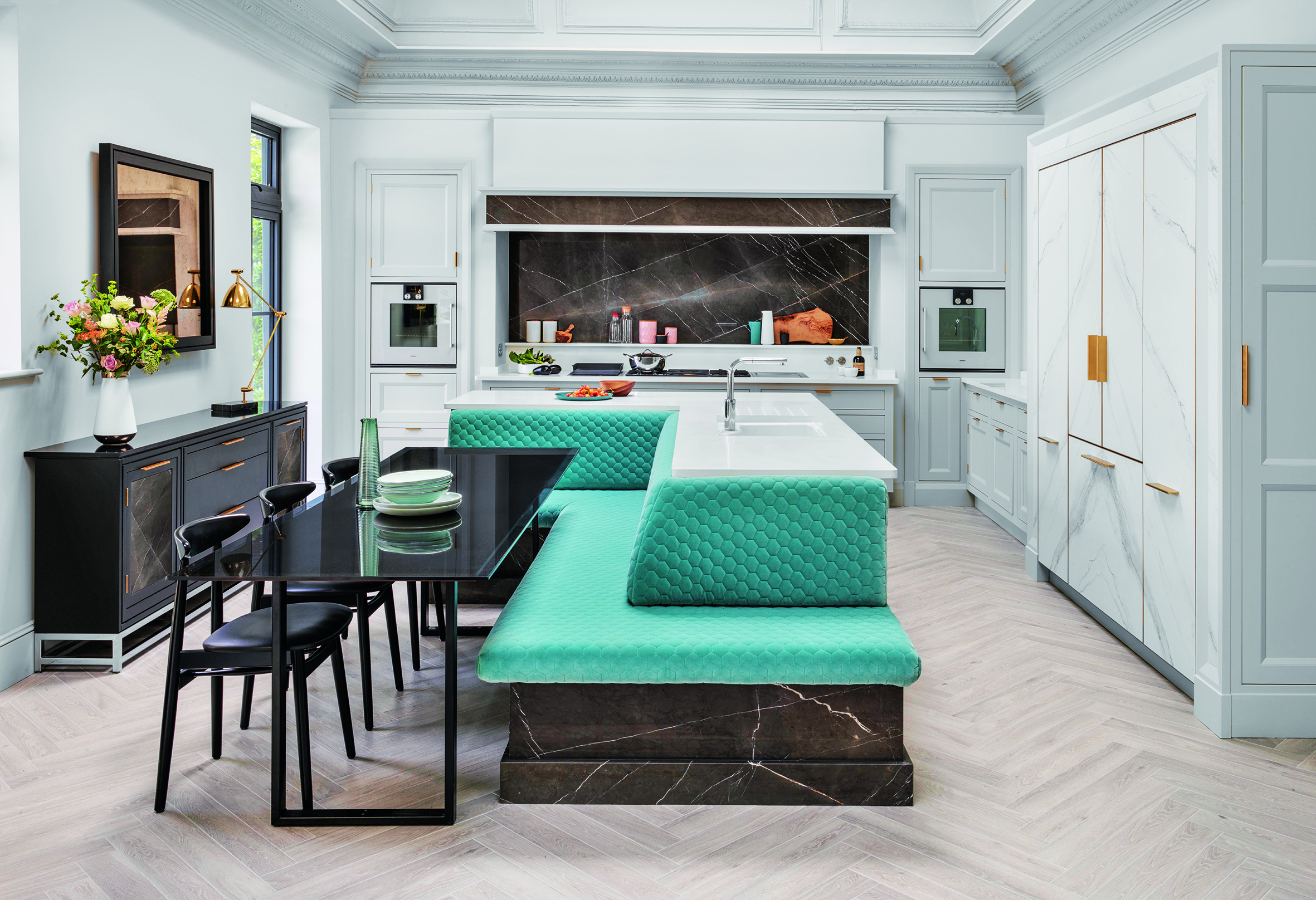 Kitchen island ideas featuring turquoise banquette seating and a black dining table in a large white scheme.