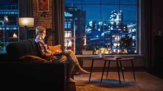 A woman sitting on the couch with a computer using her laptop in the evening 