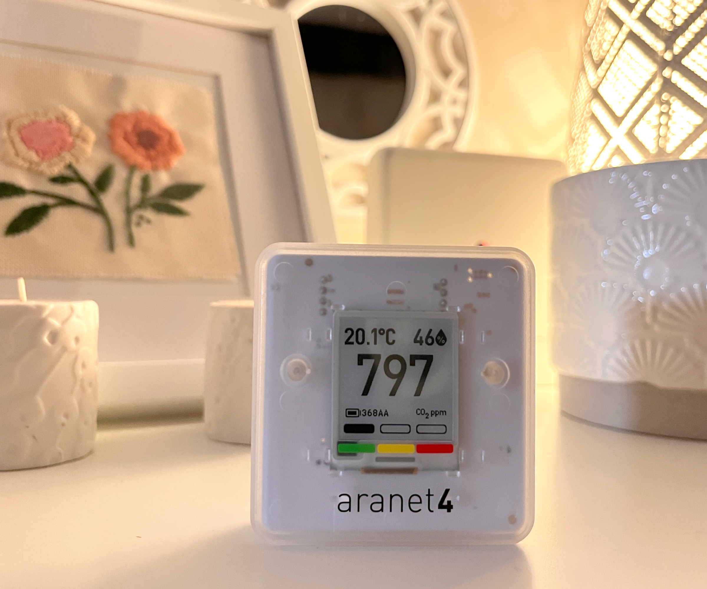Aranet4 Home monitor on cream chest of drawers with picture, candles and mirror in background