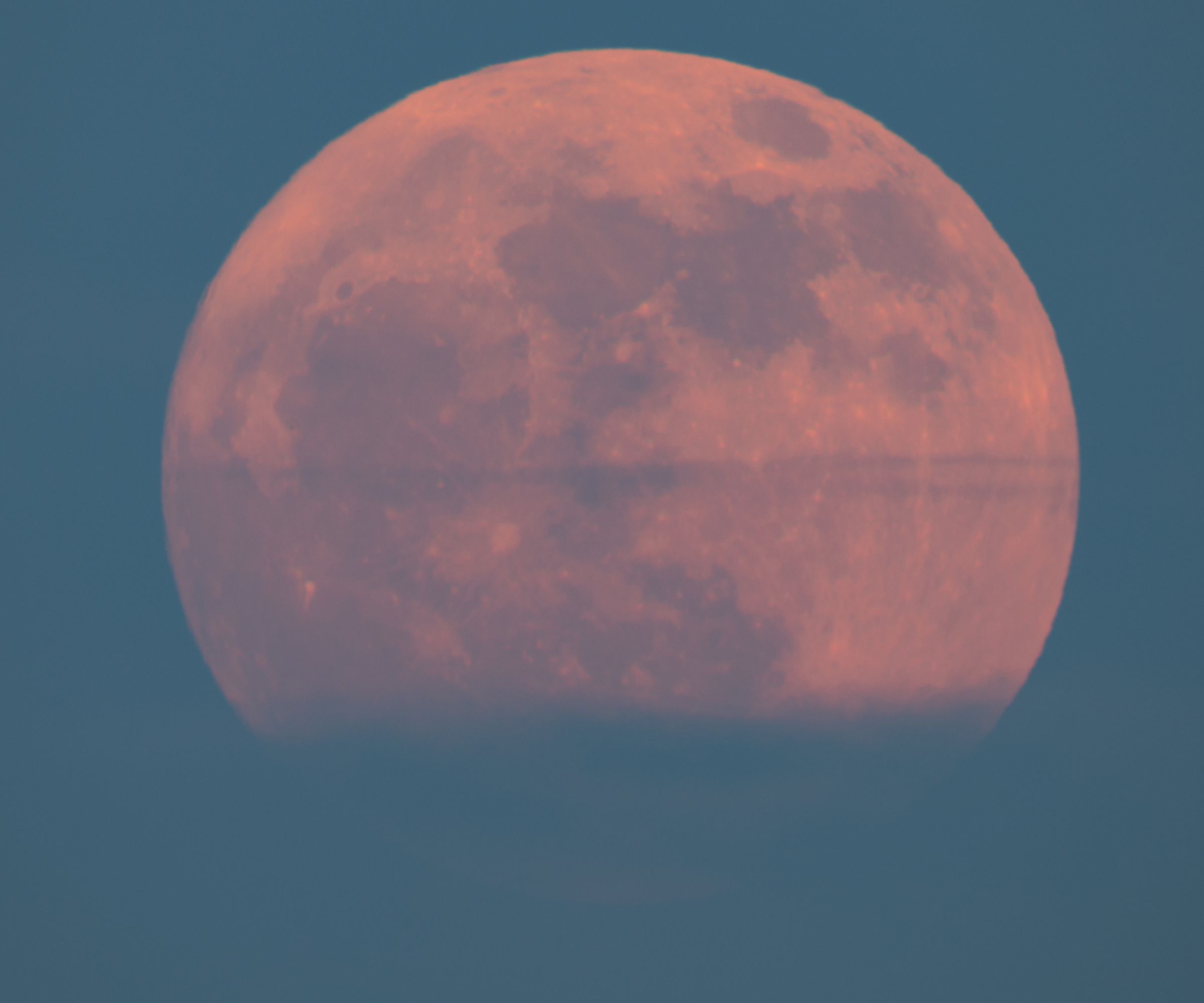 Super strawberry moon rising over the sea, a reddish full moon rising over the sea on a summer night. full moon