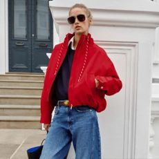 Woman wears red Zara windbreaker, blue jeans and navy knit