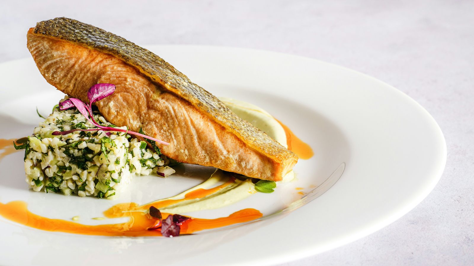 White dish of salmon resting on a block of coriander rice