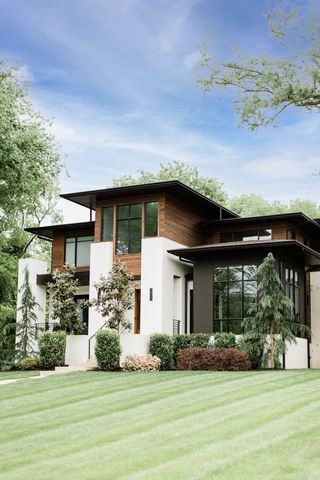 House exterior in white with wood detail and lawn and planting in front