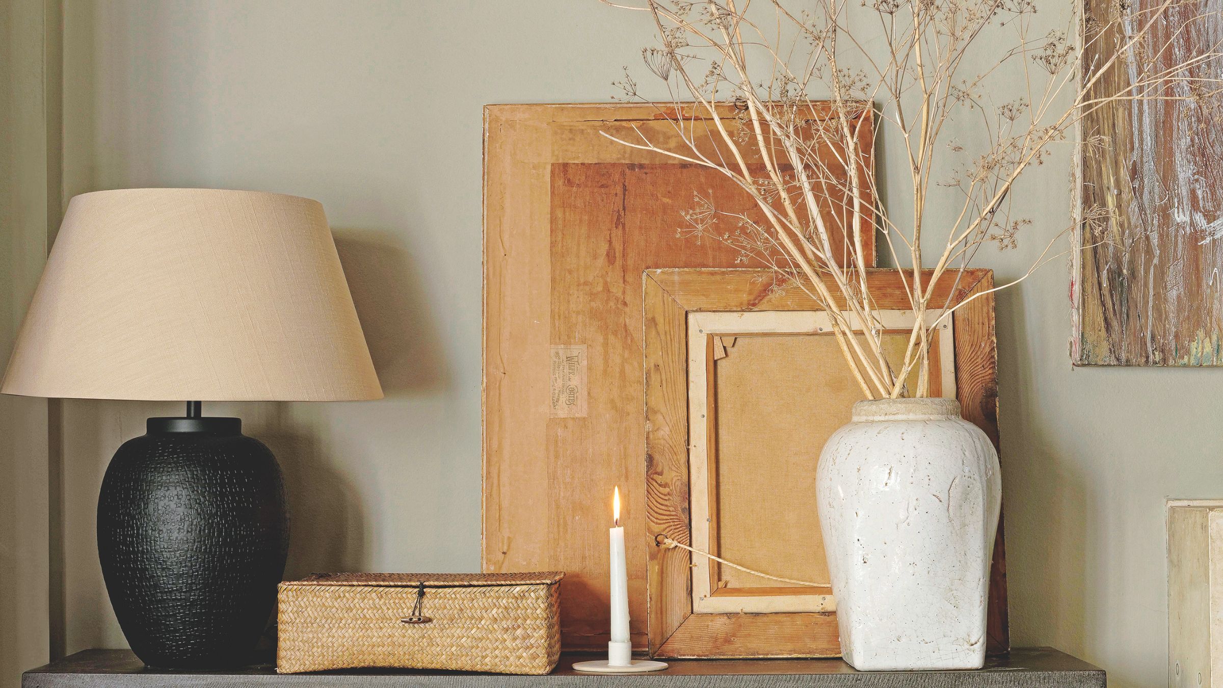 A console table against a wall with a vase, light and candle on it
