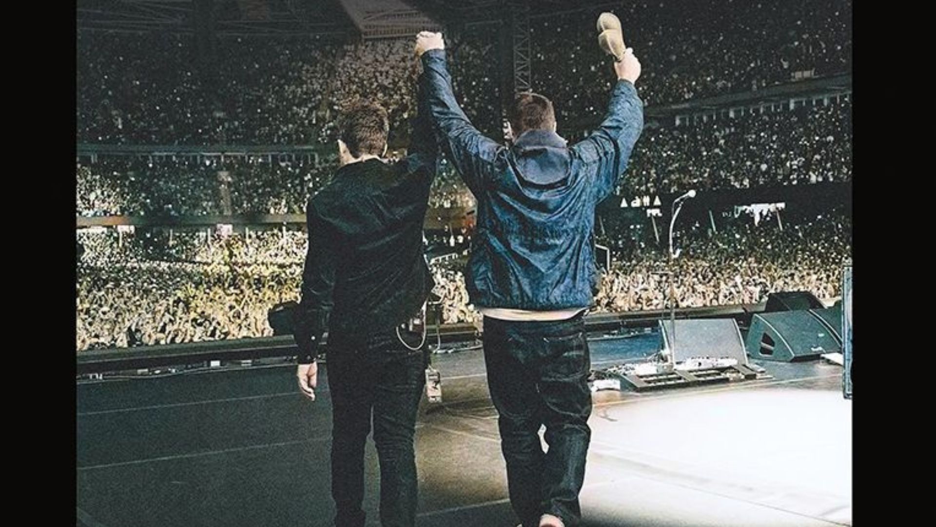 a film camera shot of Liam and Noel walking out onstage at Wembley