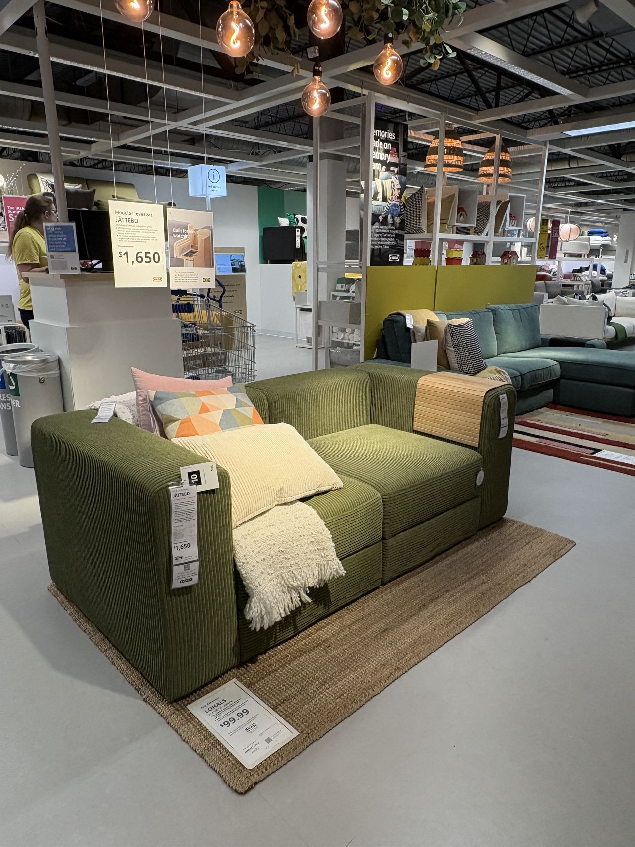 a low profile green couch with pillows sitting in a showroom.
