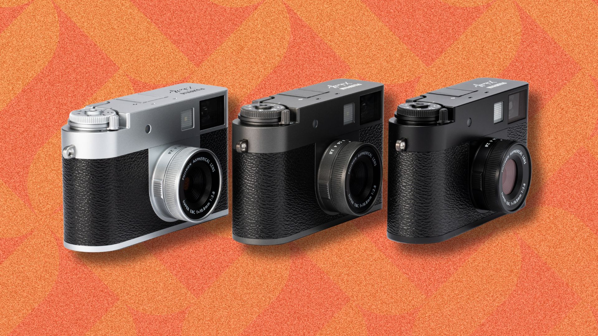 an image of three Fujifilm half x cameras, one in each colourway. The three cameras are against an orange patterned background