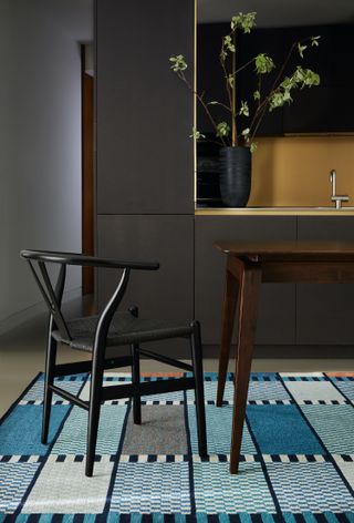 A dining table and chair with patterned rug in blue tones