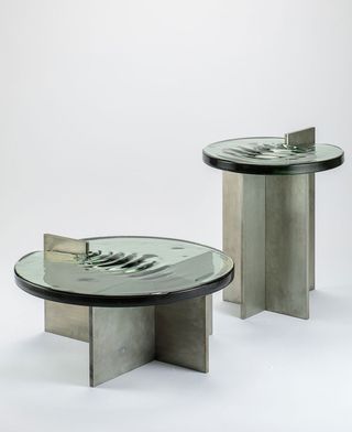 Tables made of round green glass tops mimicking the movement of water surface, with geometric concrete bases