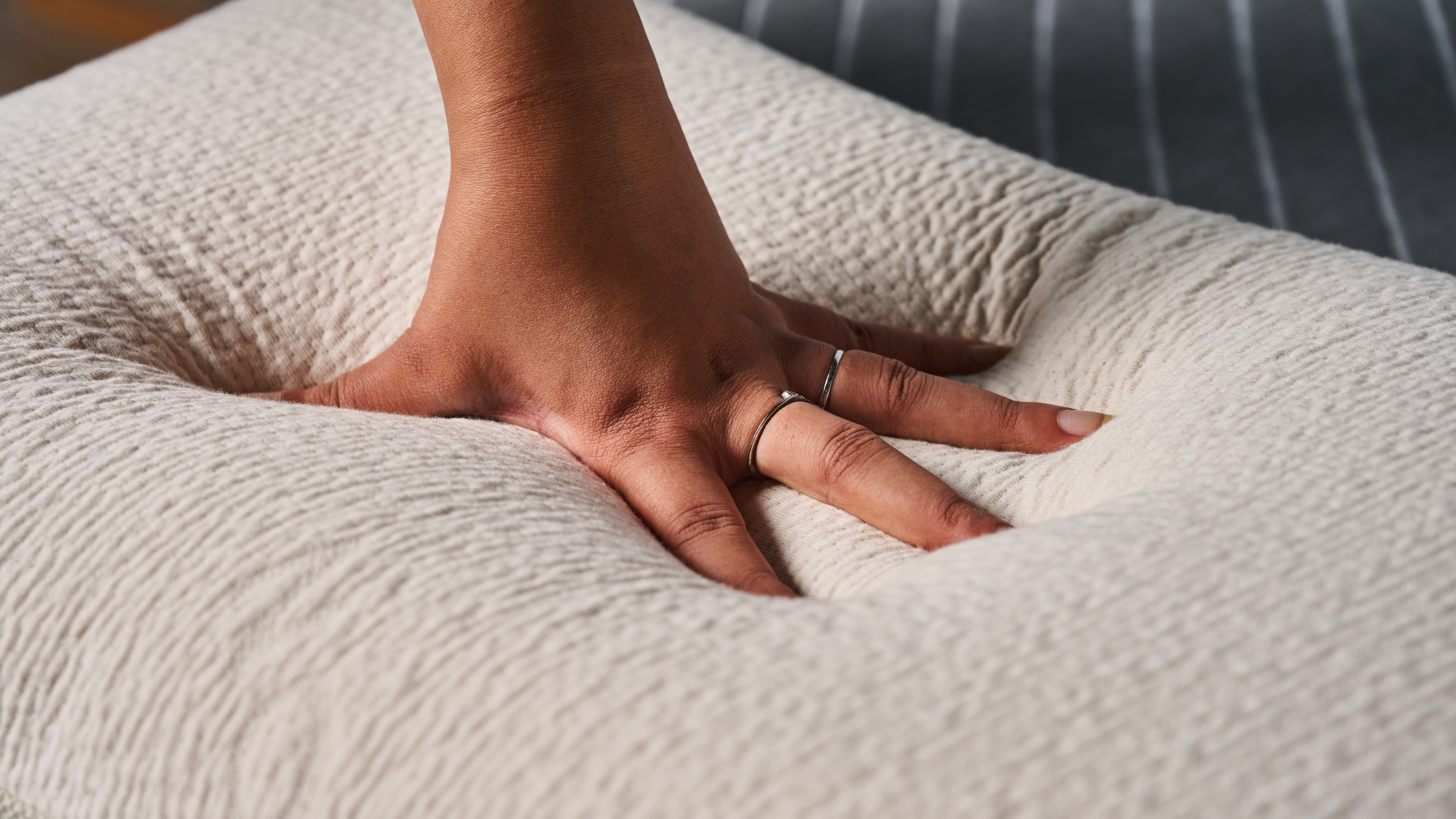 Hands pressed into the Avocado Molded Latex Pillow to gauge firmness/depth