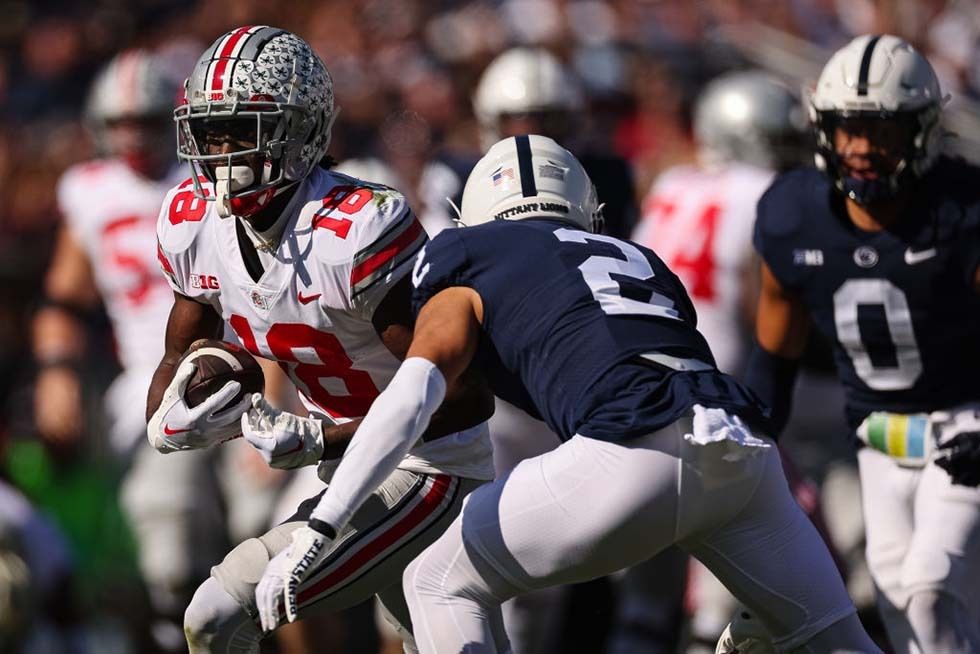 Marvin Harrison Jr. #18 of the Ohio State Buckeyes carries the ball as Keaton Ellis #2 of the Penn State Nittany Lions defends during the first half at Beaver Stadium on October 29, 2022