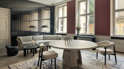 round white dining table in a large living room with white dining chairs and grey sofa