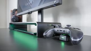 A side view of the Razer Monitor Stand Chroma in a desk setup with a controller plugged in