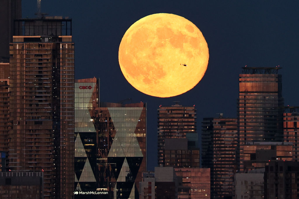 An orange sphere over gold and silver buildings against a dark blue background