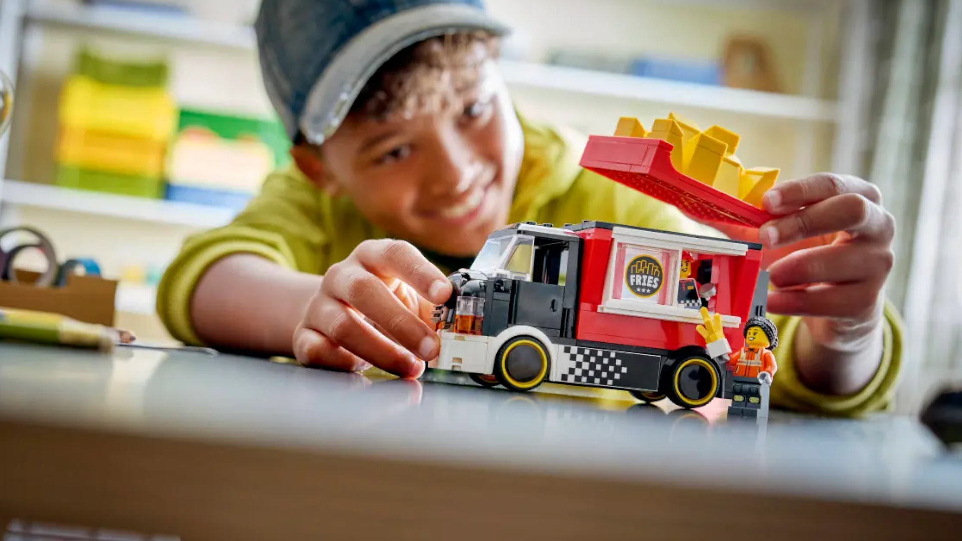 A child smiles while playing with the Lego Fries Food Truck set at a table