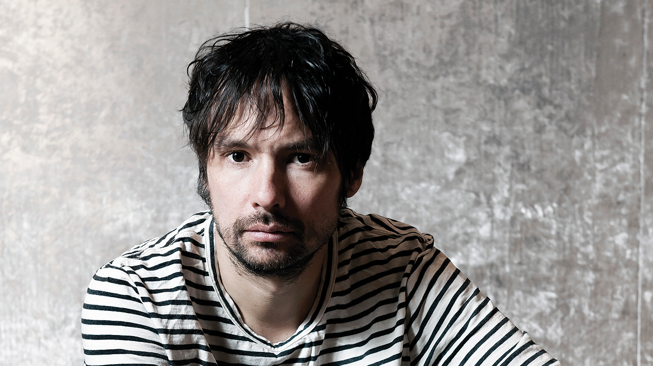 A press shot of Bruce Soord, sat down in a striped top