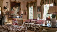 Traditional living room with pale pink walls, antique art, pelmet curtains and flora sofa and ottoman