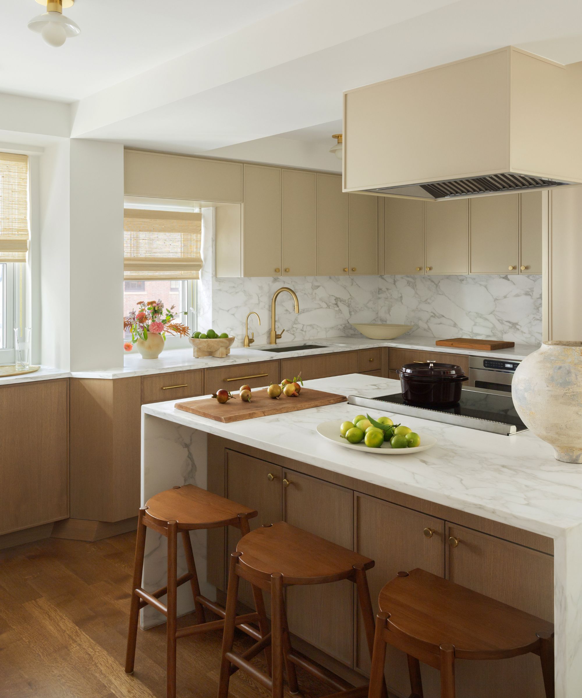 A warm neutral kitchen with wooden cabinets, cream upper cabinets, and a marble backsplash