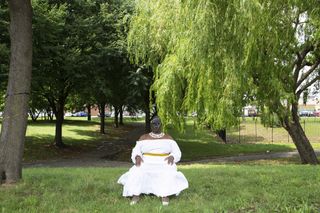 black woman in white dress wearing a mask, in a park