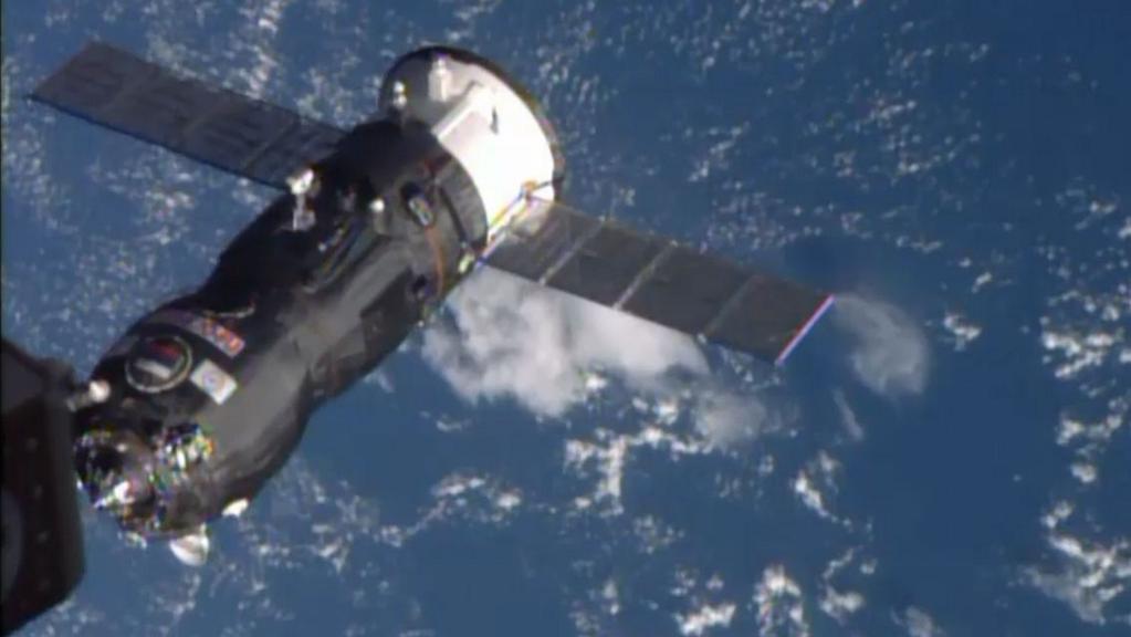 An unmanned robotic vehicle docks to the International Space Station above the blue Atlantic Ocean.